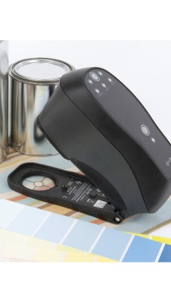 X-Rite handheld colour-matching device beside paint tins and colour swatches